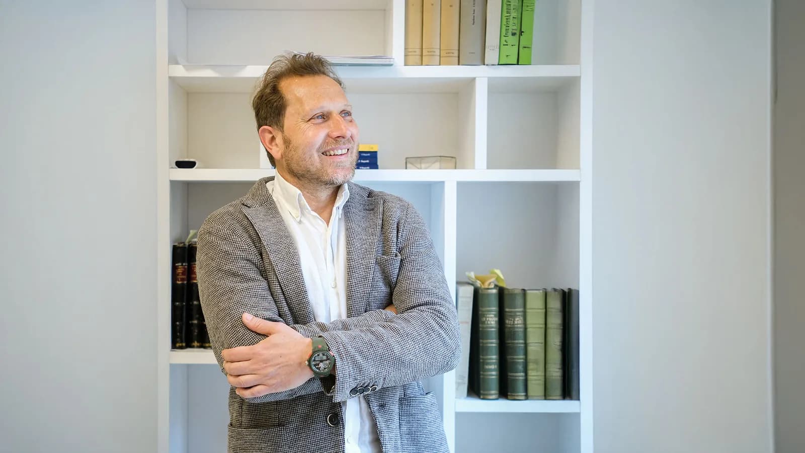 Il Dott. Paolo Ghidoni a braccia conserte davanti alla libreria dello studio